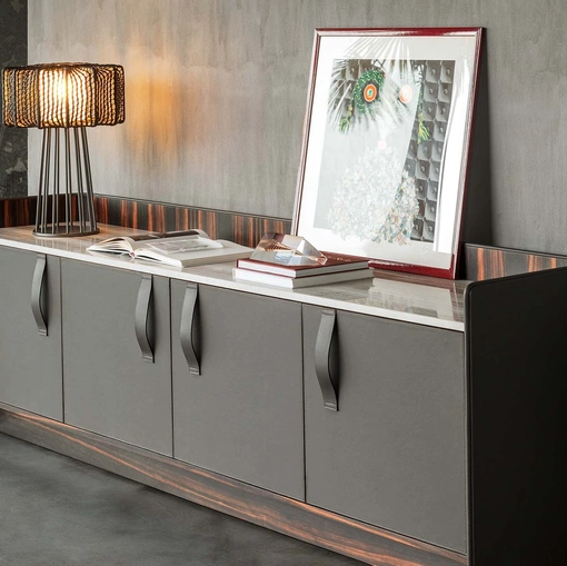 Madia Gentleman con struttura in legno multistrato curvato rivestito esternamente in pelle grigia, internamente in ebano con top in marmo di Flou